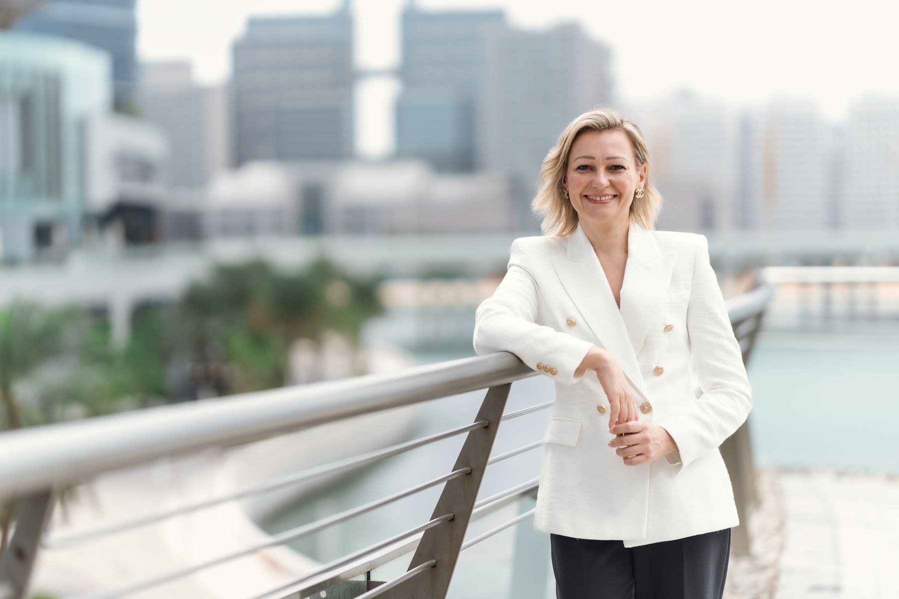Sofia Borodulina-Abboud leaning on a railing with the Abu Dhabi skyline behind her